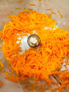 Shredded carrots in the bowl of the food processor