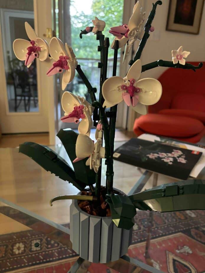 An orchid made out of legos on a glass table