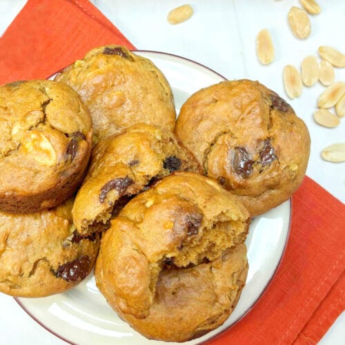 A plate of Banana Peanut Butter Chocolate Chip Muffins on an orange napkin