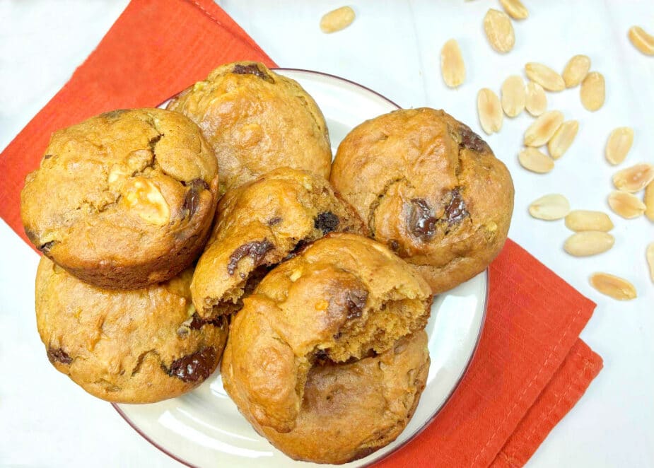 A plate of Banana Peanut Butter Chocolate Chip Muffins on an orange napkin