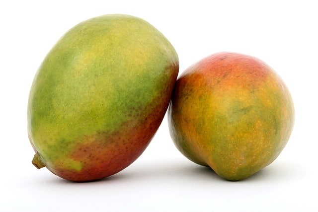 2 green and red mangos on a white counter