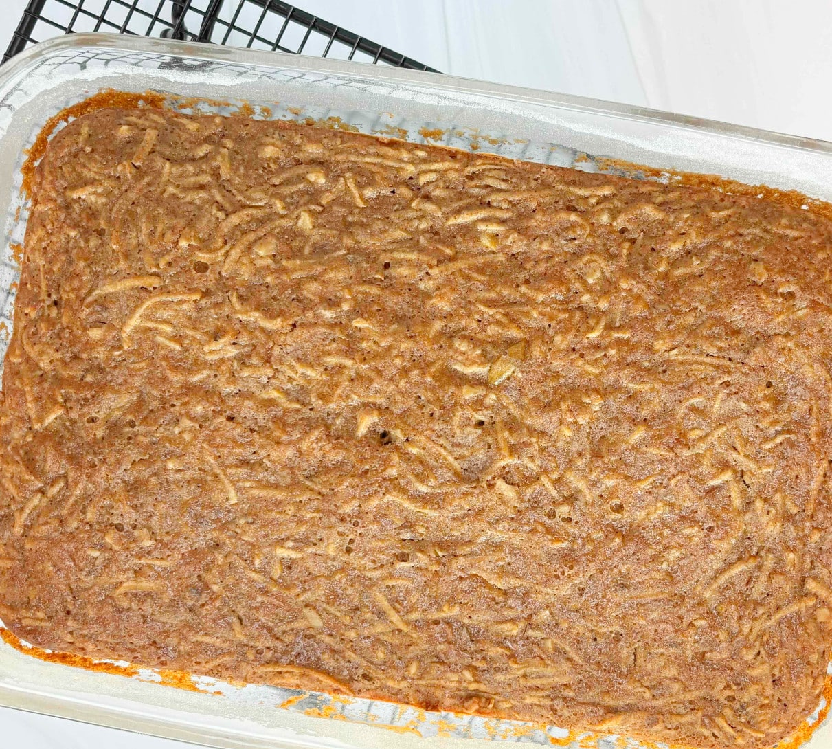 A glass cake pan filled with baked spiced apple cake before cutting.