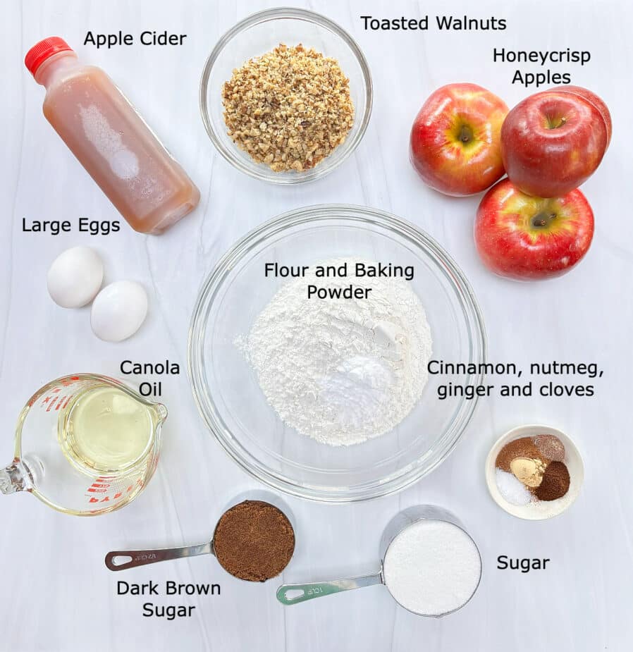 All the ingredients used to make the spiced apple cake on a marble counter top.