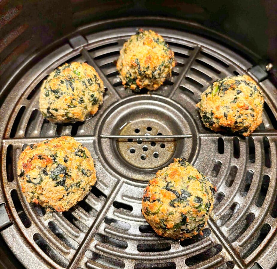 Cooked spinach balls in an air fryer basket