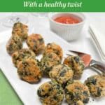 A white serving platter with spinach balls. A ramekin of tomato sauce is in the background.