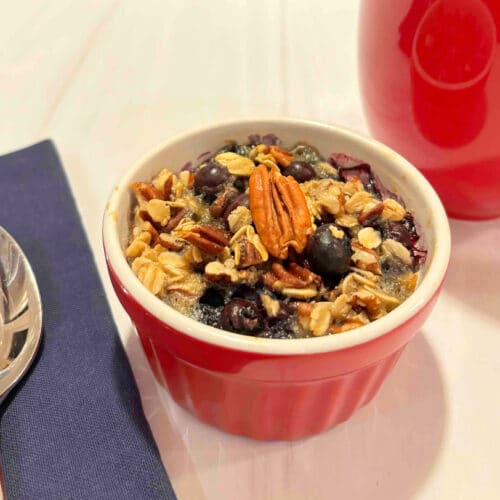 A blueberry baked oat cup with a cup of coffee on the side.