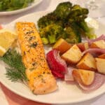 A salmon fillet, roasted red potatoes, and broccoli on a white plate.