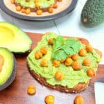 A slice of whole grain bread spread with avocado and topped with crunchy chickpeas.