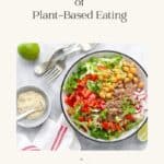 A salad bowl filled with plant based foods on a white table.